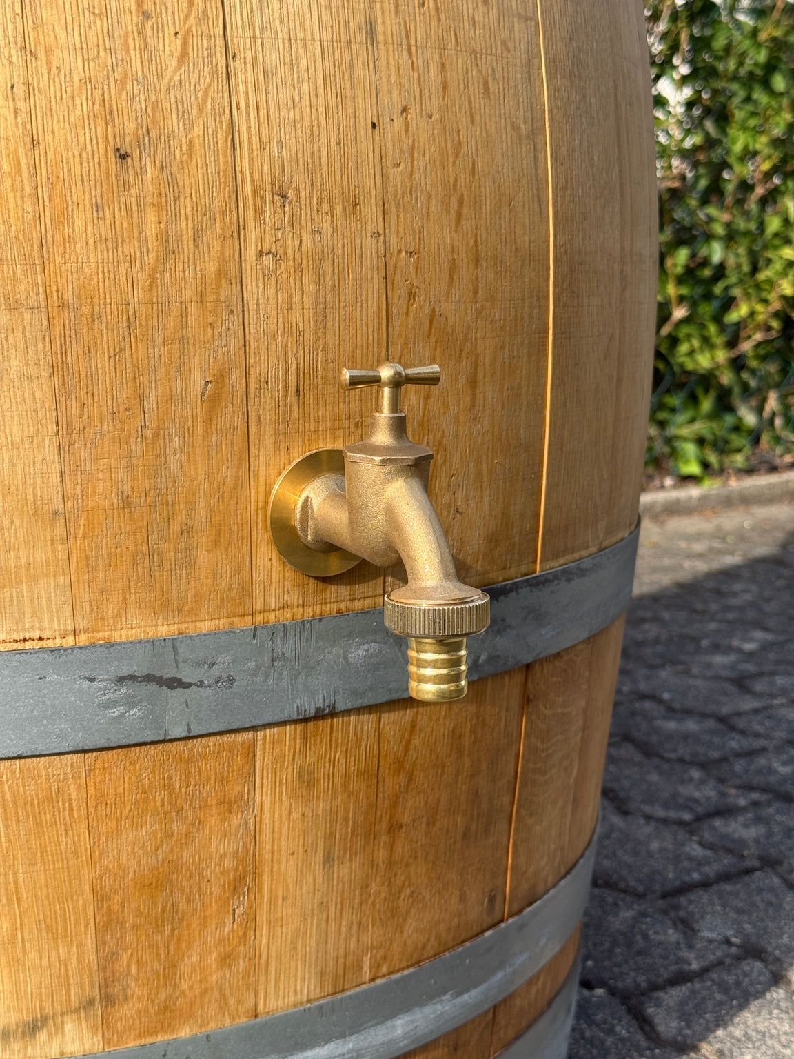 Messing-Auslaufhahn mit Schlauchtülle an der geölten Regentonne aus Eiche